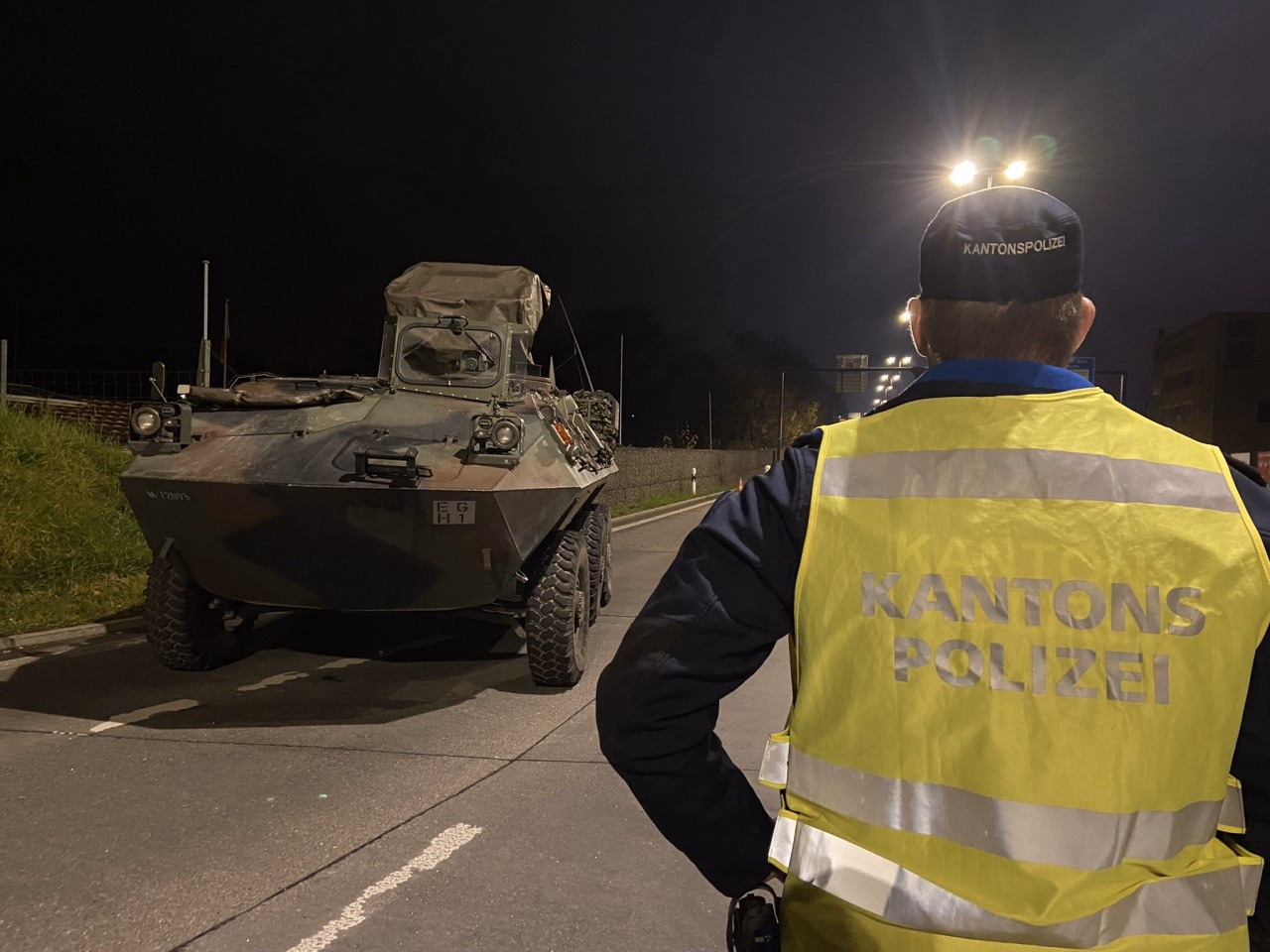 Panzerfahrzeug der Schweizer Armee und Polizist der Kantonspolizei Aargau.