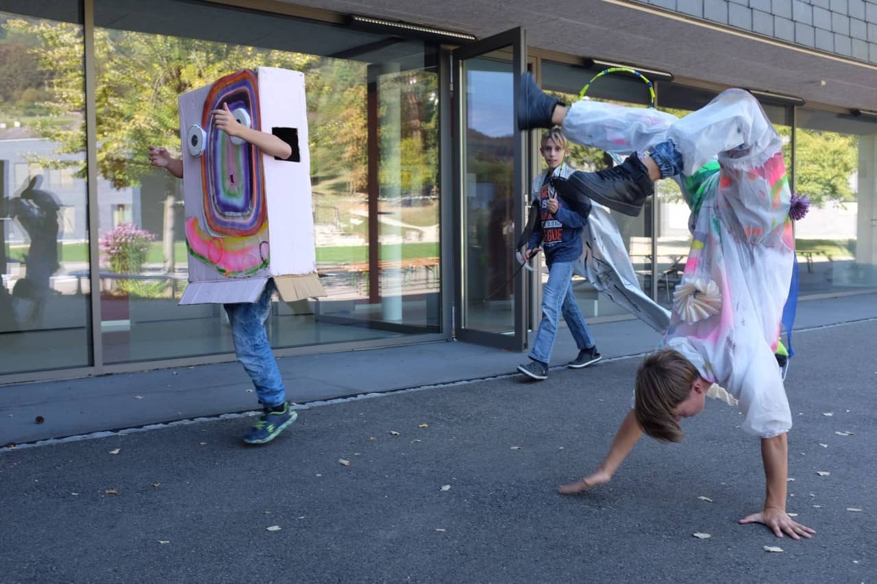 Drei Schüler in Kostümen tollen über den Pausenplatz