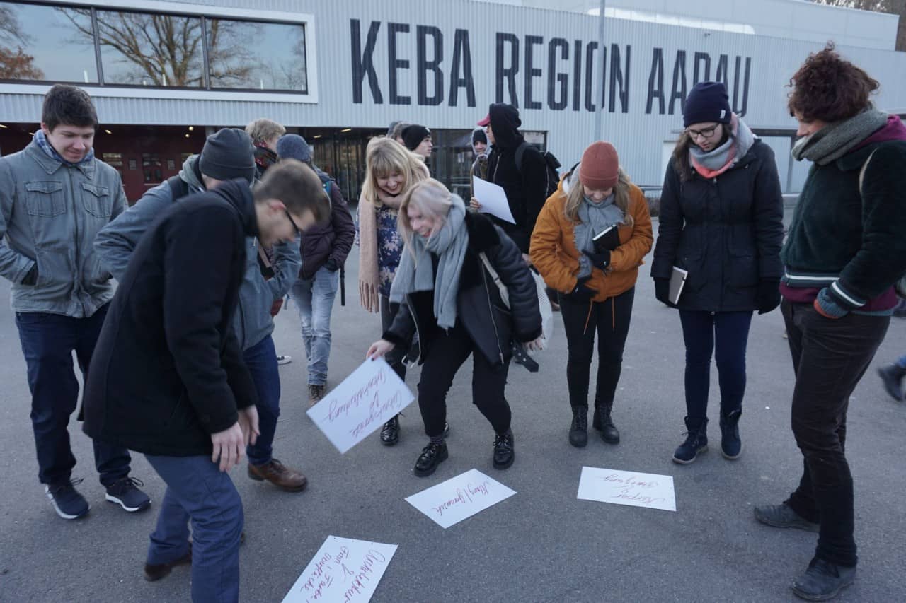 Schülerinnen und Schüler stehen vor Zetteln auf dem Platz vor der Keba