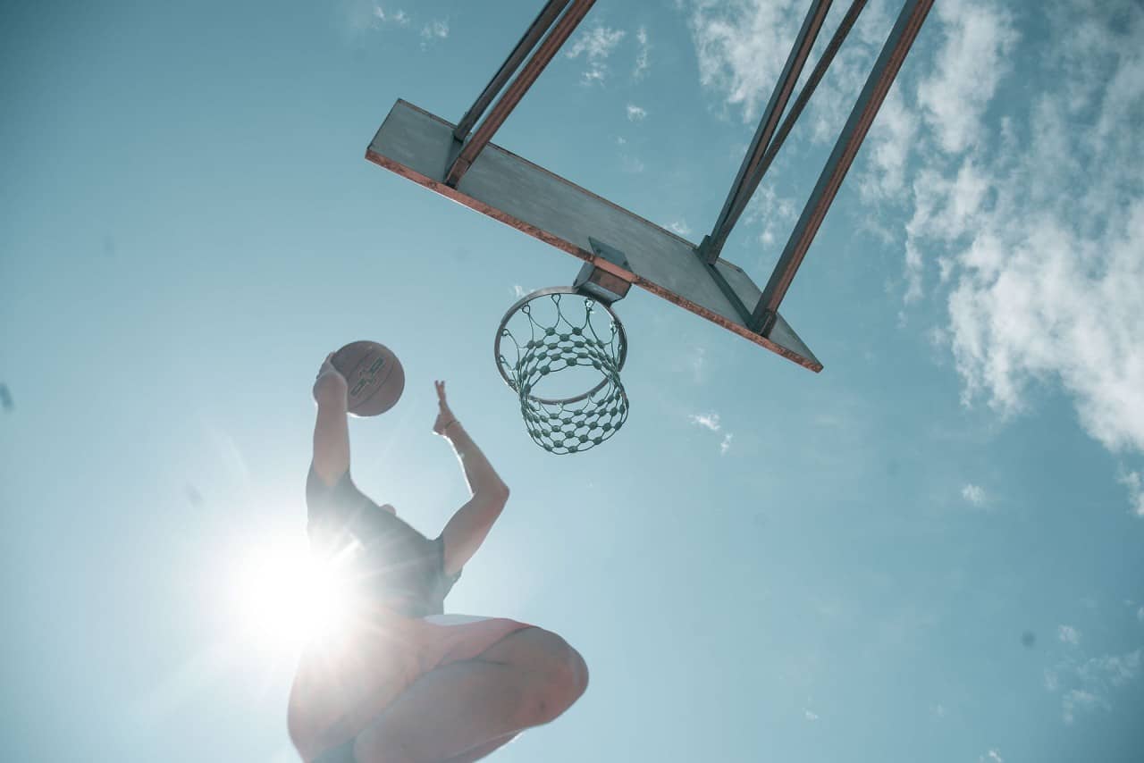 Ein Jugendlicher spielt auf den Basketballkorb.