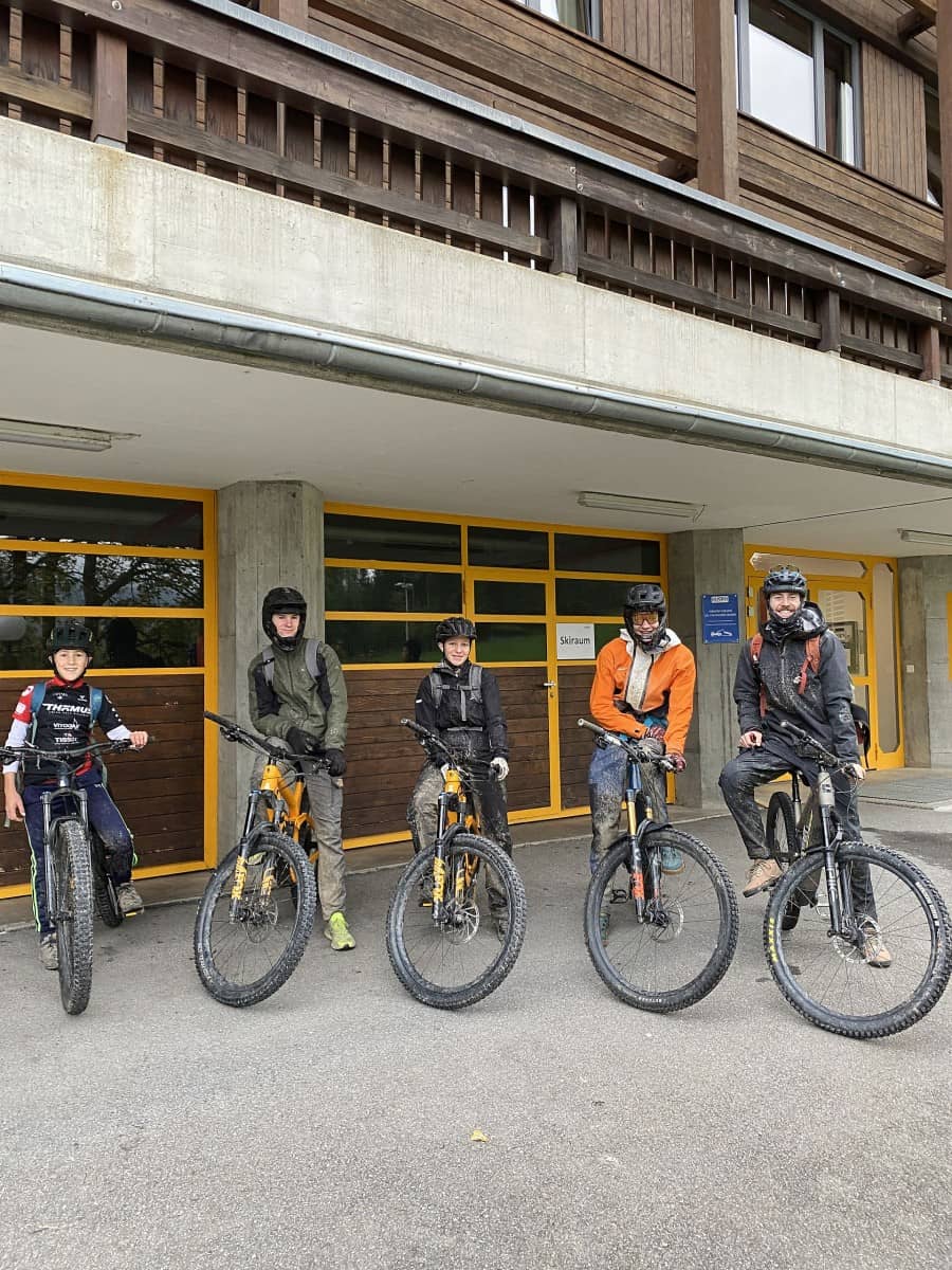 Fünf Mountainbiker stehen in einer Reihe für ein Gruppenfoto.