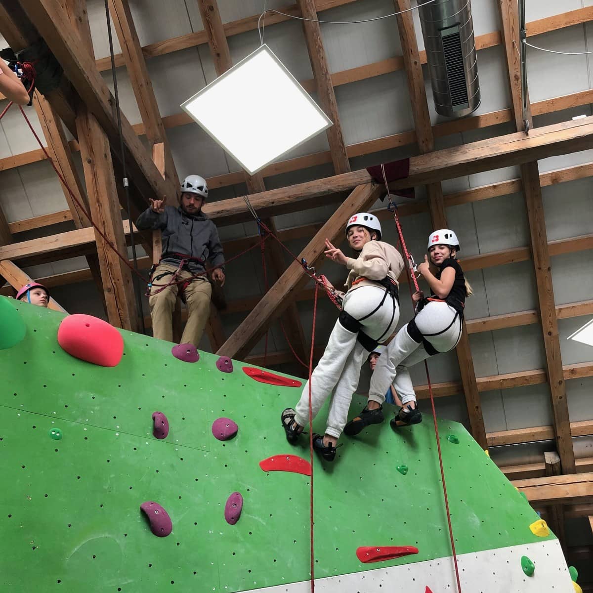 Jugendliche sind an der Indoor-Kletterwand.