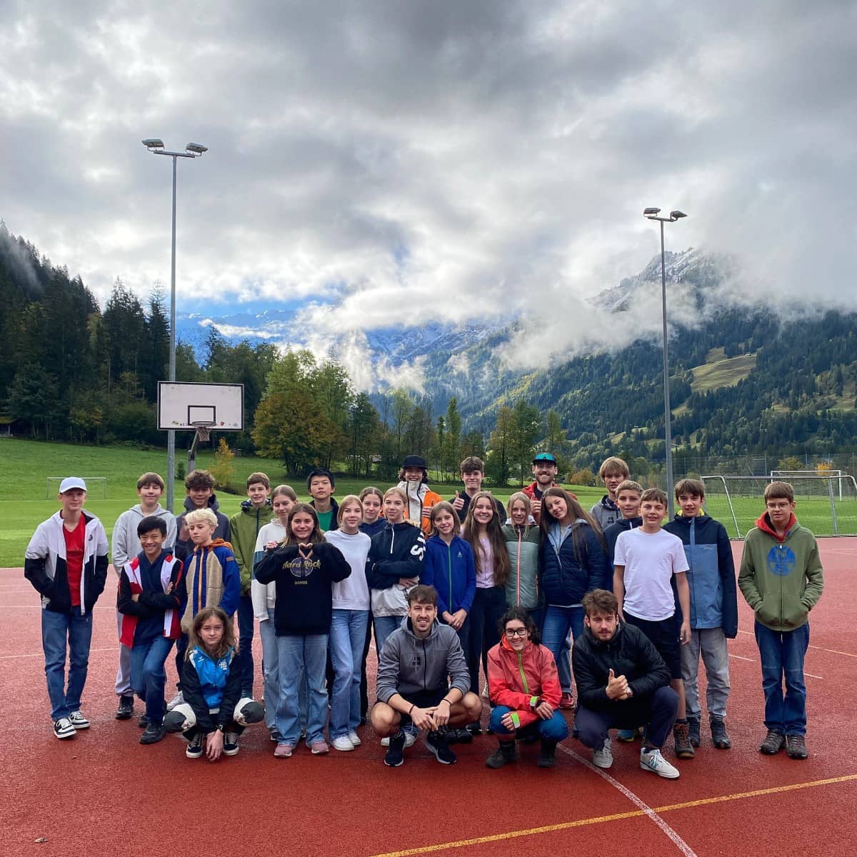 Jugendliche stehen auf dem Sportplatz zusammen für ein Gruppenfoto.