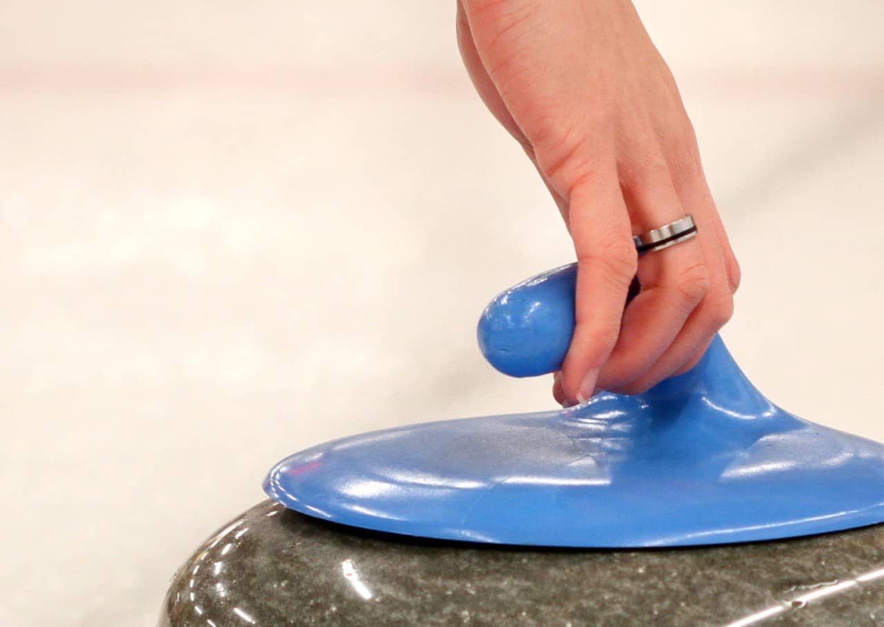 Eine Hand am Curlingstein.
