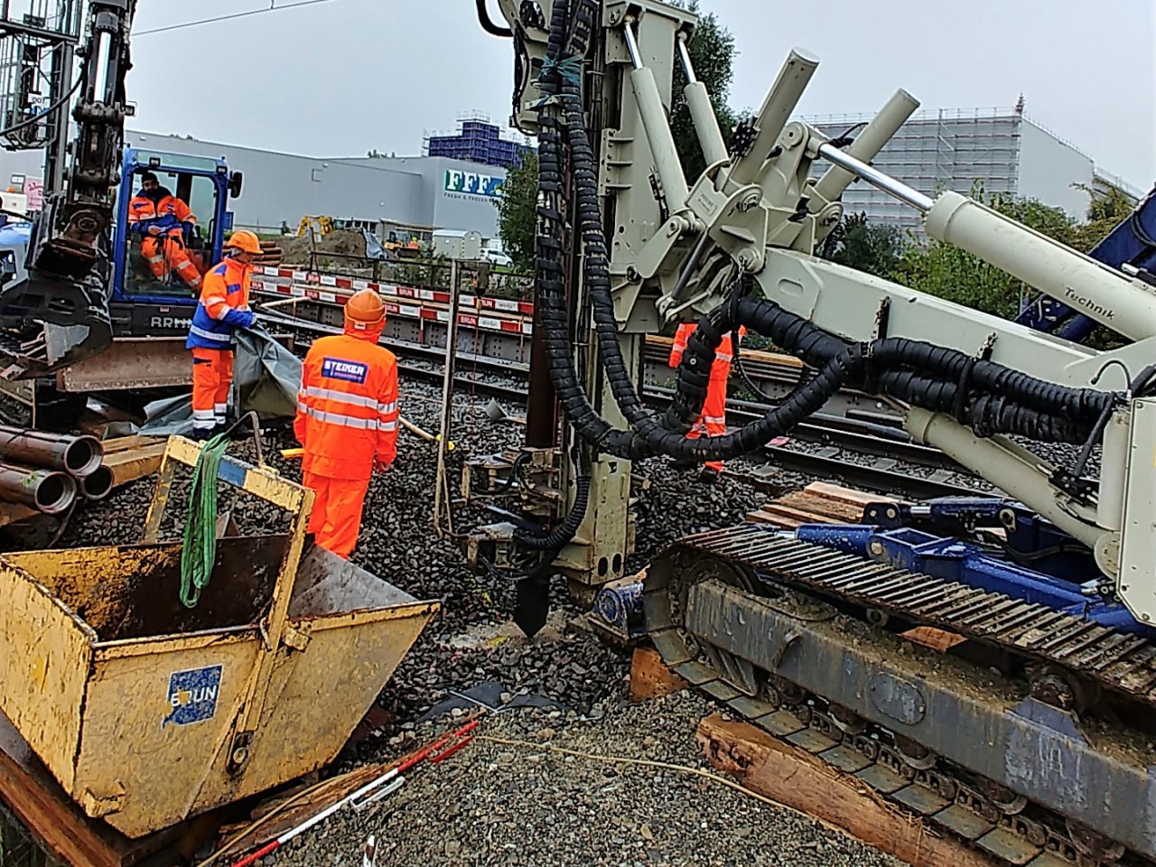 Bohrgerät für Mikropfähle mit Arbeiternden entlang der Bahnline 